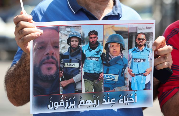 A demonstrator holds a poster featuring Reuters journalist Hussam al-Masri, Mohammed Salama, who worked for Qatar-based broadcaster Al Jazeera, Moaz Abu Taha, a freelance journalist who worked with several news organizations and occasionally contributed to Reuters, Mariam Abu Dagga, who freelanced for the Associated Press and other outlets, and Ahmed Abu Aziz, who were all killed in Israeli strikes on Nasser hospital in the southern Gaza Strip, during a protest in solidarity with journalists in Gaza, in Sidon, Lebanon, August 27, 2025. REUTERS/Aziz Taher