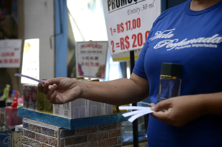 Tomaz Silva/Agência Brasil Vendedora entrega fragrâncias aos pedestres em loja na tradicional área de compras do Saara, no centro do Rio de Janeiro